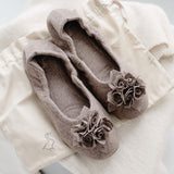 Grace Wool – Hausschuh aus Wolle mit Stoffblume, Paar liegend auf Stoffbeutel, Farbe Trüffel.